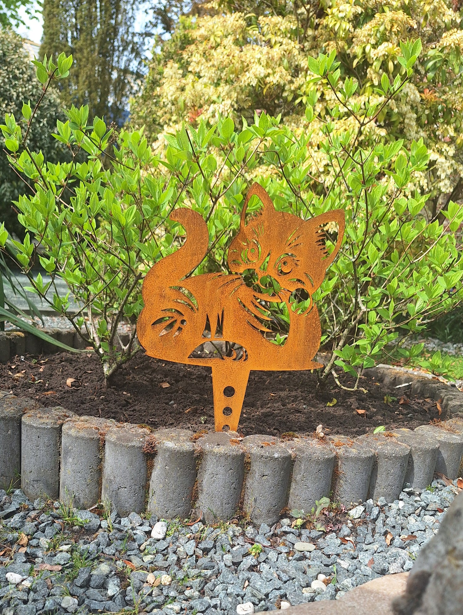 Cortenstalen tuinprikker in de vorm van een kat, gebruikt als tuindecoratie in een groene tuin